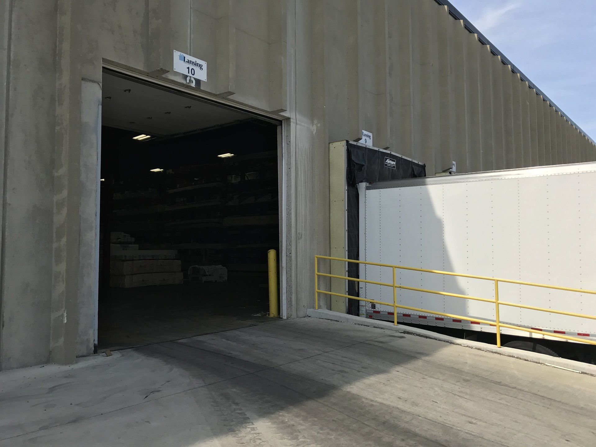 A truck is being loaded into a warehouse with the door open.