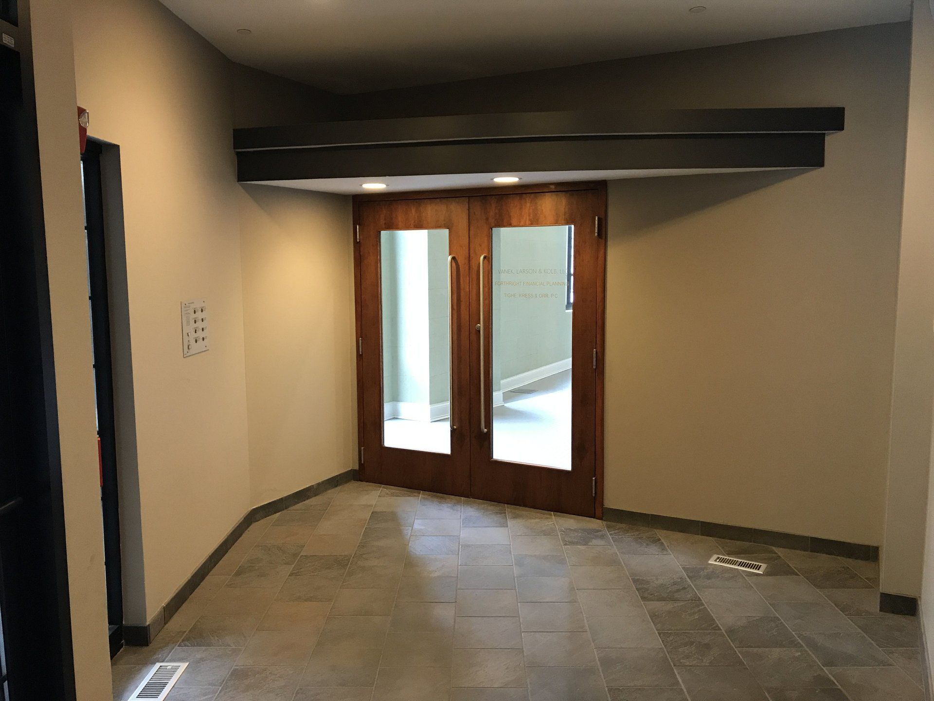 A large empty room with a wooden door and a tiled floor.