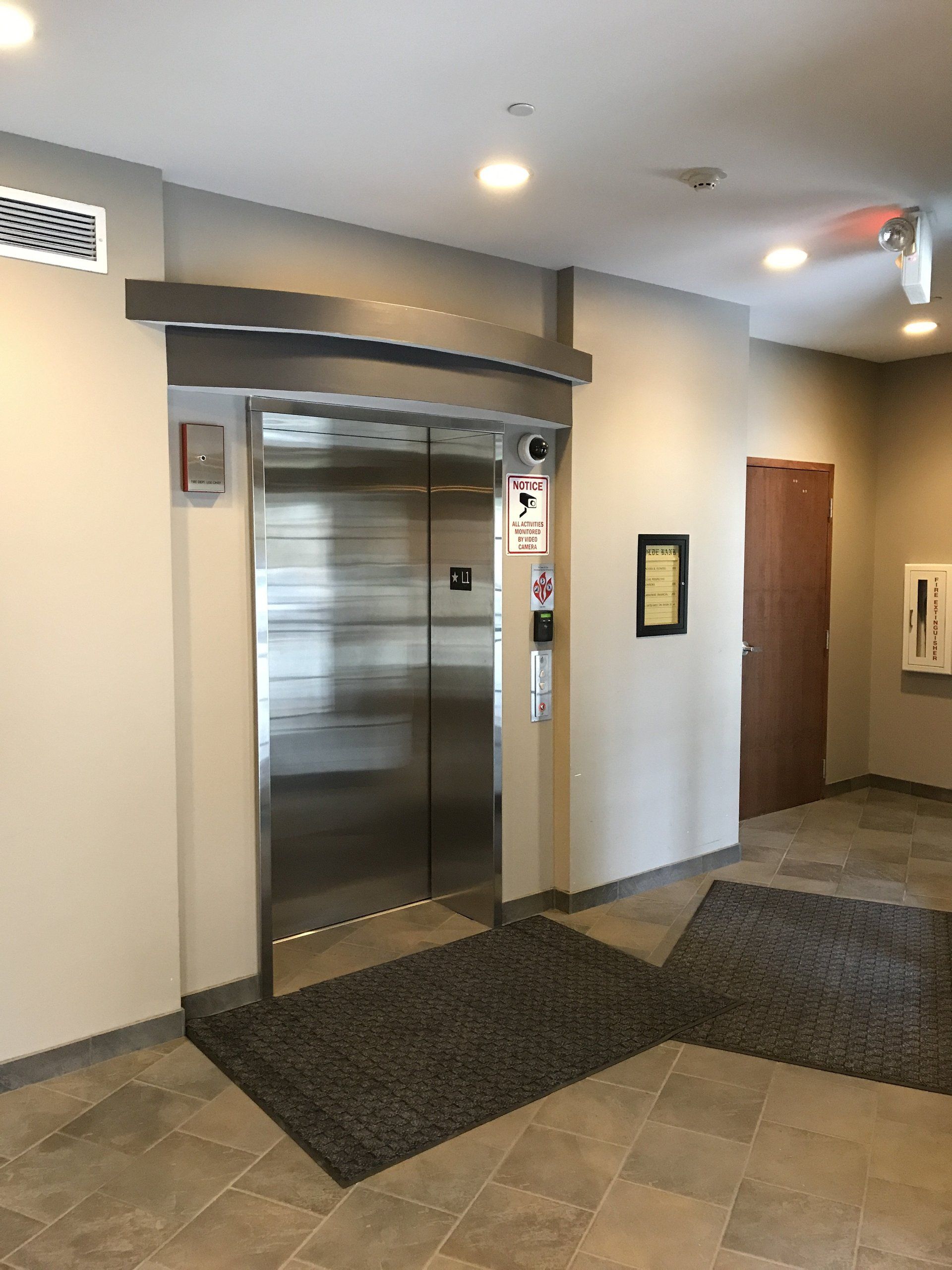A stainless steel elevator is in the middle of a hallway.