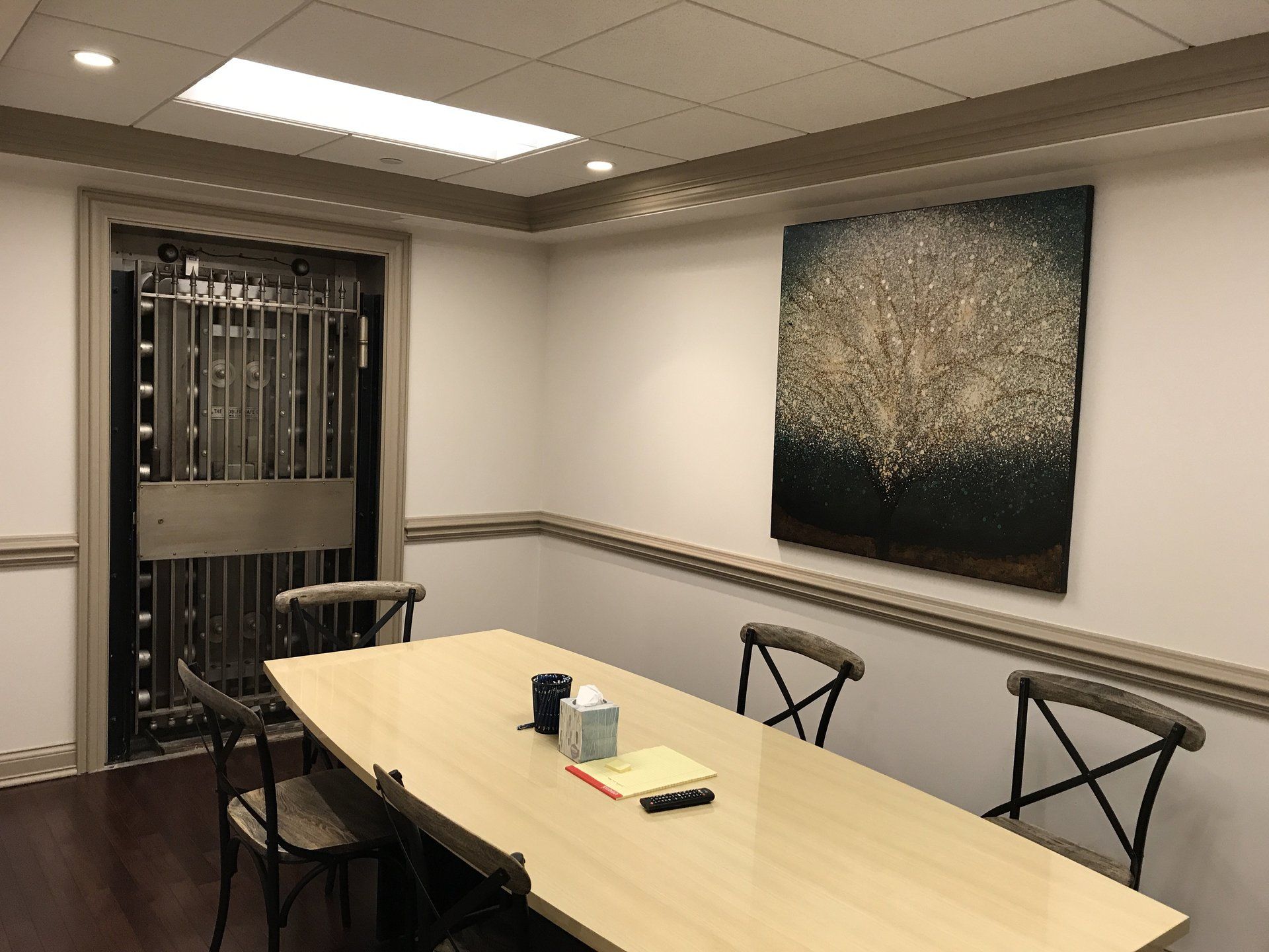 A conference room with a table and chairs and a painting on the wall.