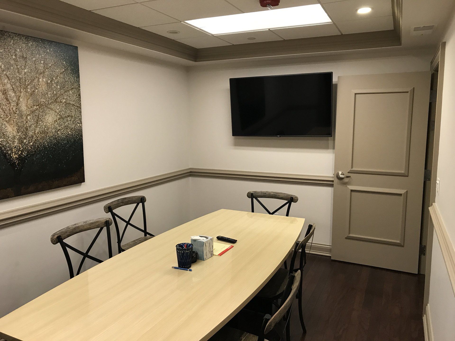 A conference room with a long table and chairs and a flat screen tv on the wall.