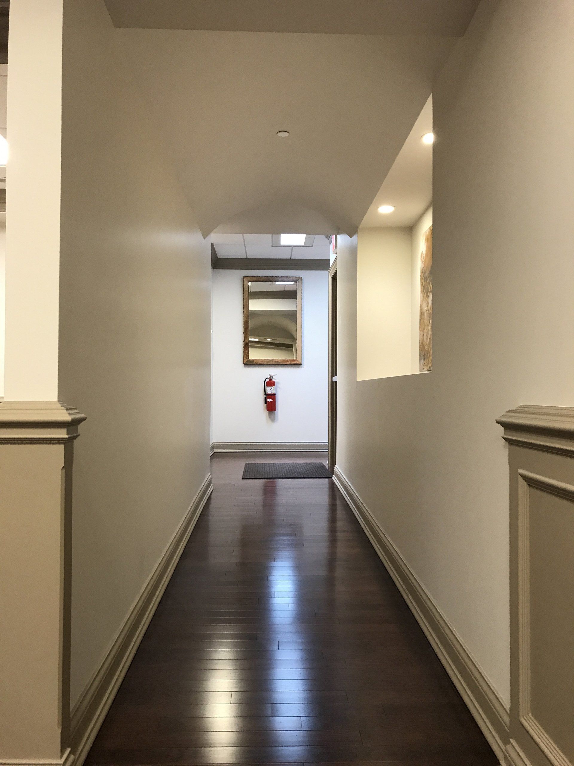 A long hallway with a fire extinguisher on the wall.