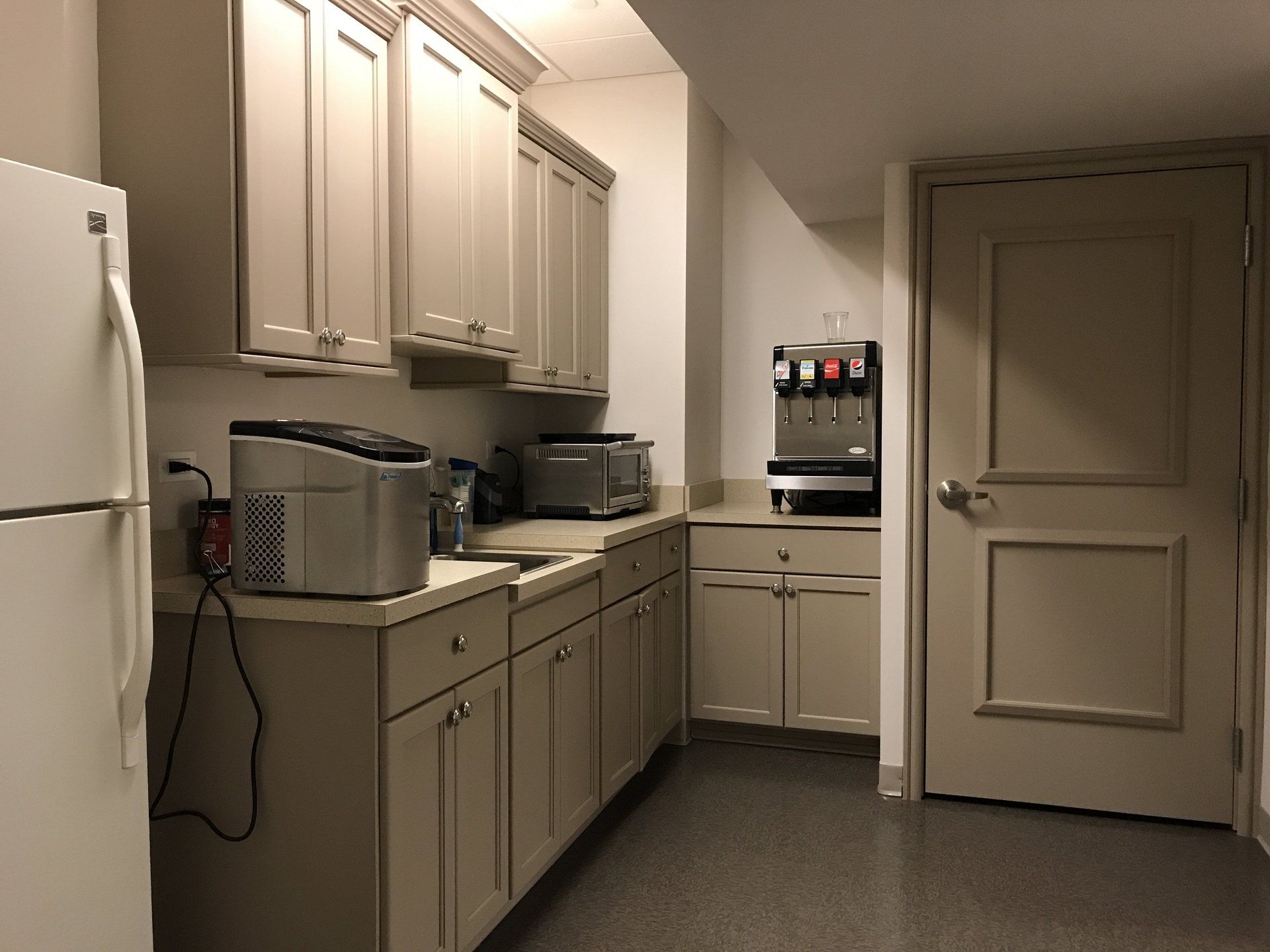 A kitchen with a refrigerator and a soda fountain