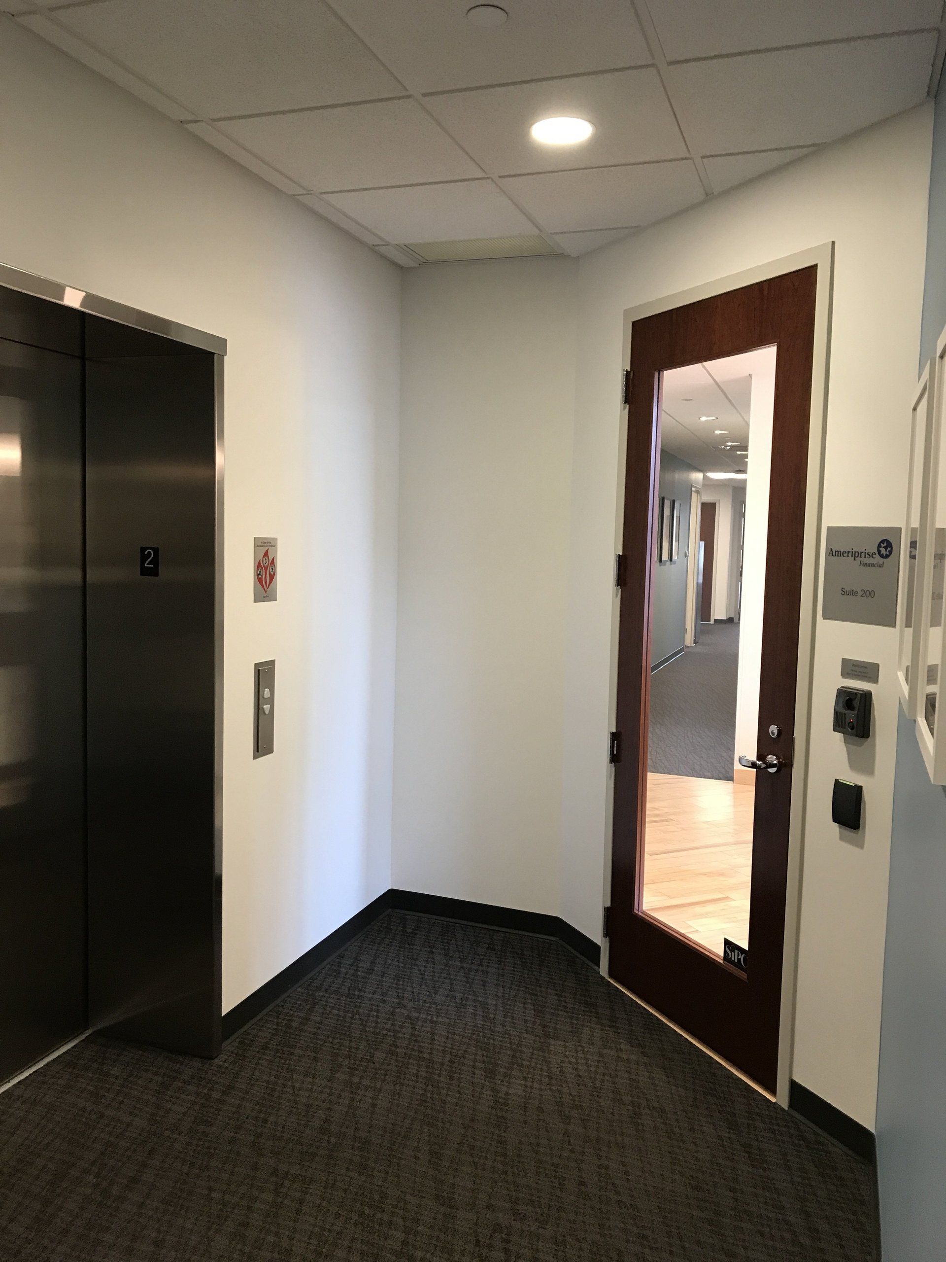 A hallway with an elevator and a glass door