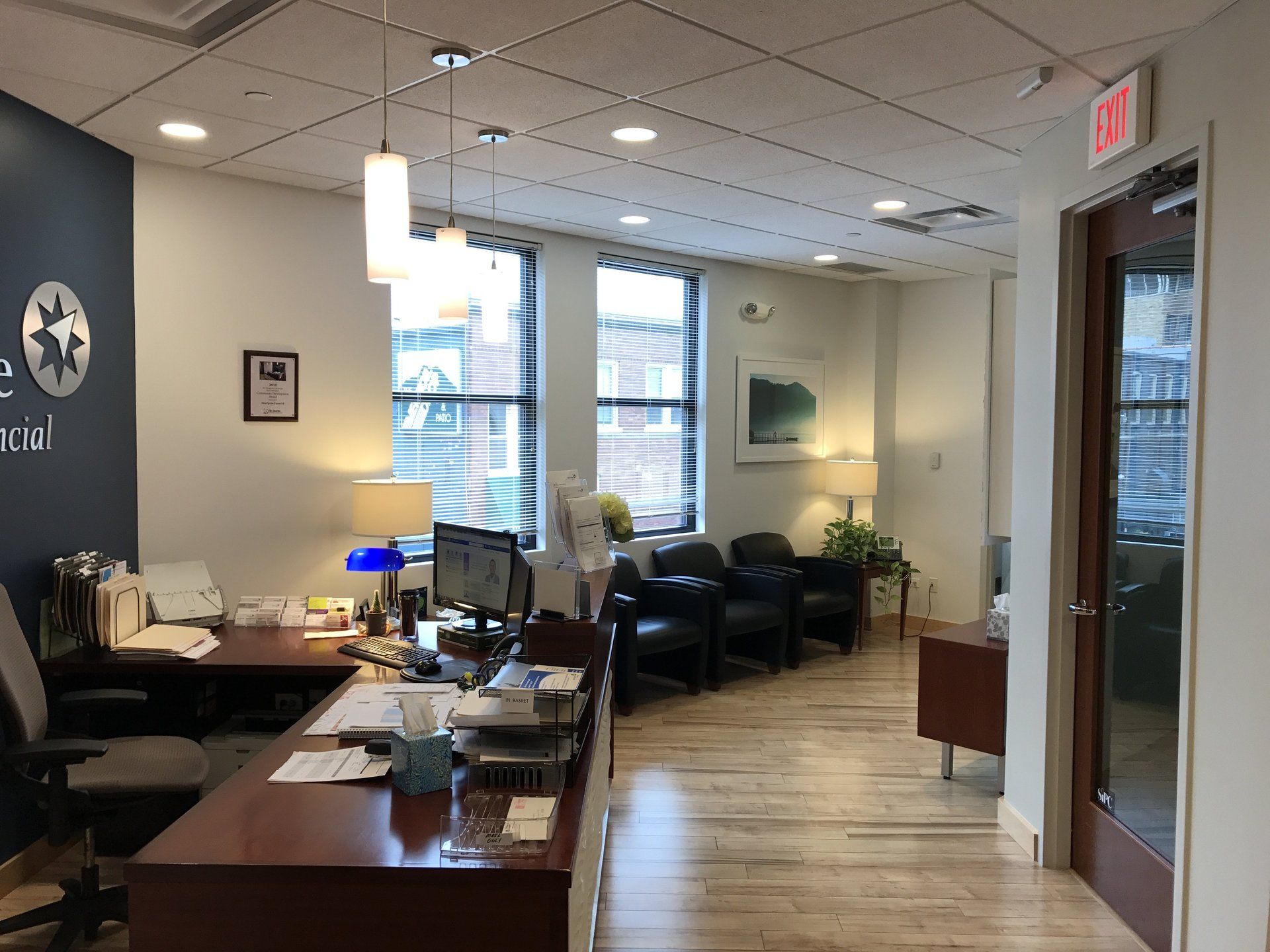 A large office with a lot of windows and a red exit sign.