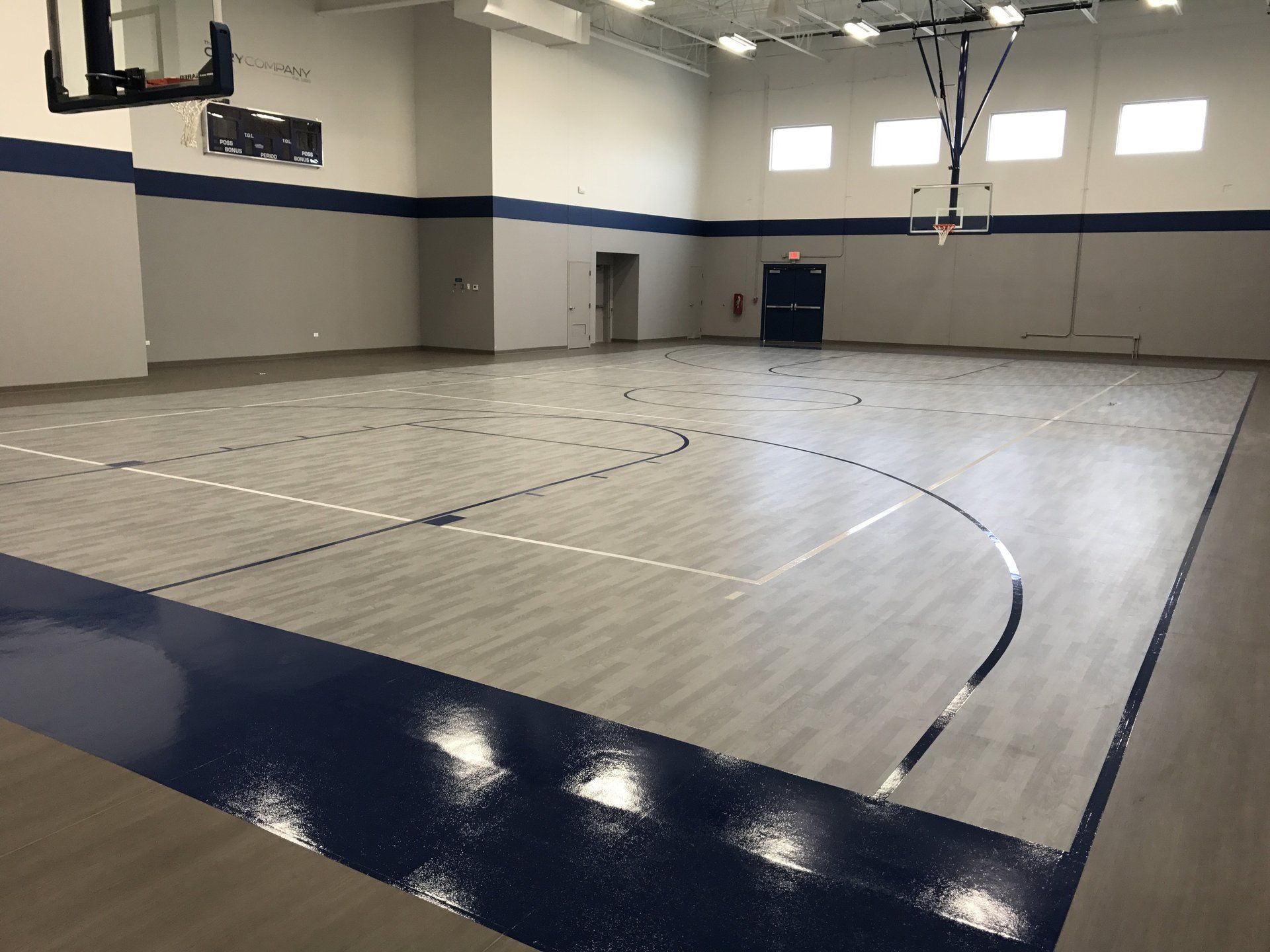 A large basketball court with a basketball hoop in a gym.