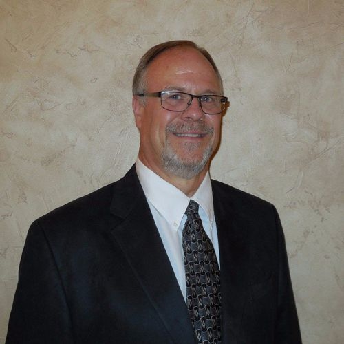 A man in a suit and tie is smiling for the camera