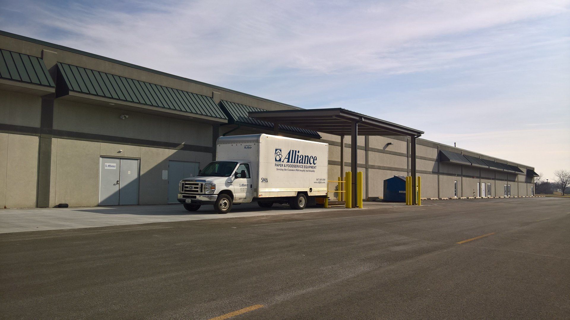 A white van is parked in front of a large building
