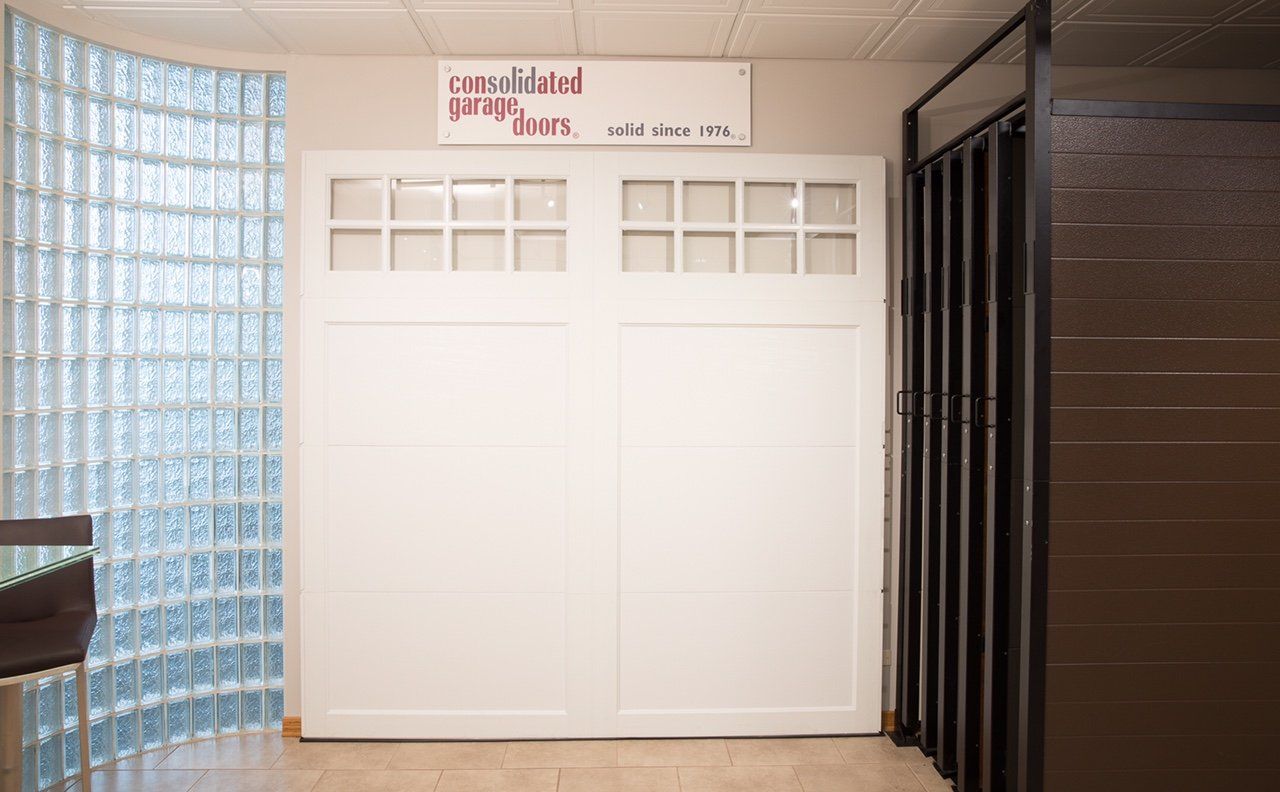 A white garage door is sitting in a room next to a glass wall.