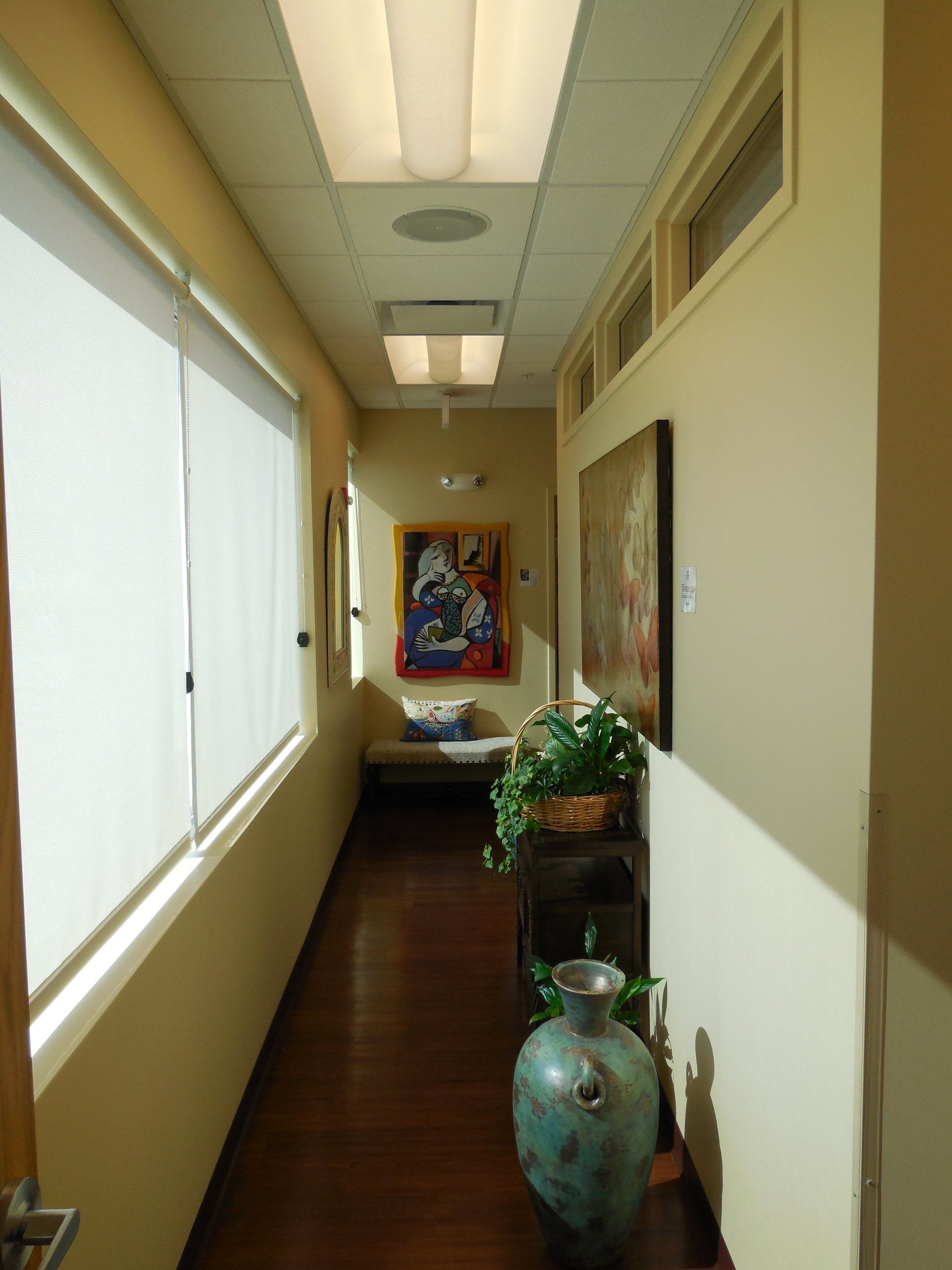 A long hallway with a vase and a painting on the wall