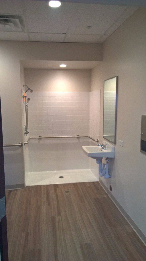 A bathroom with a sink , shower and mirror.