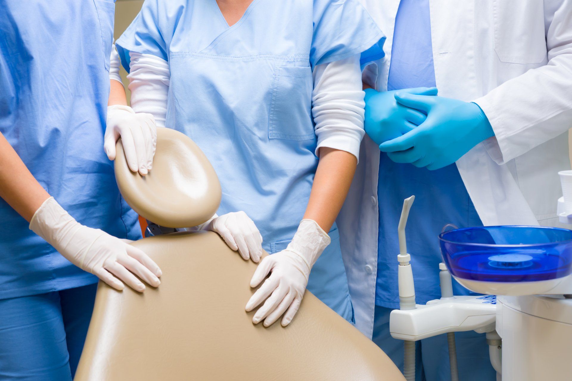 A group of dentists are standing around a dental chair.