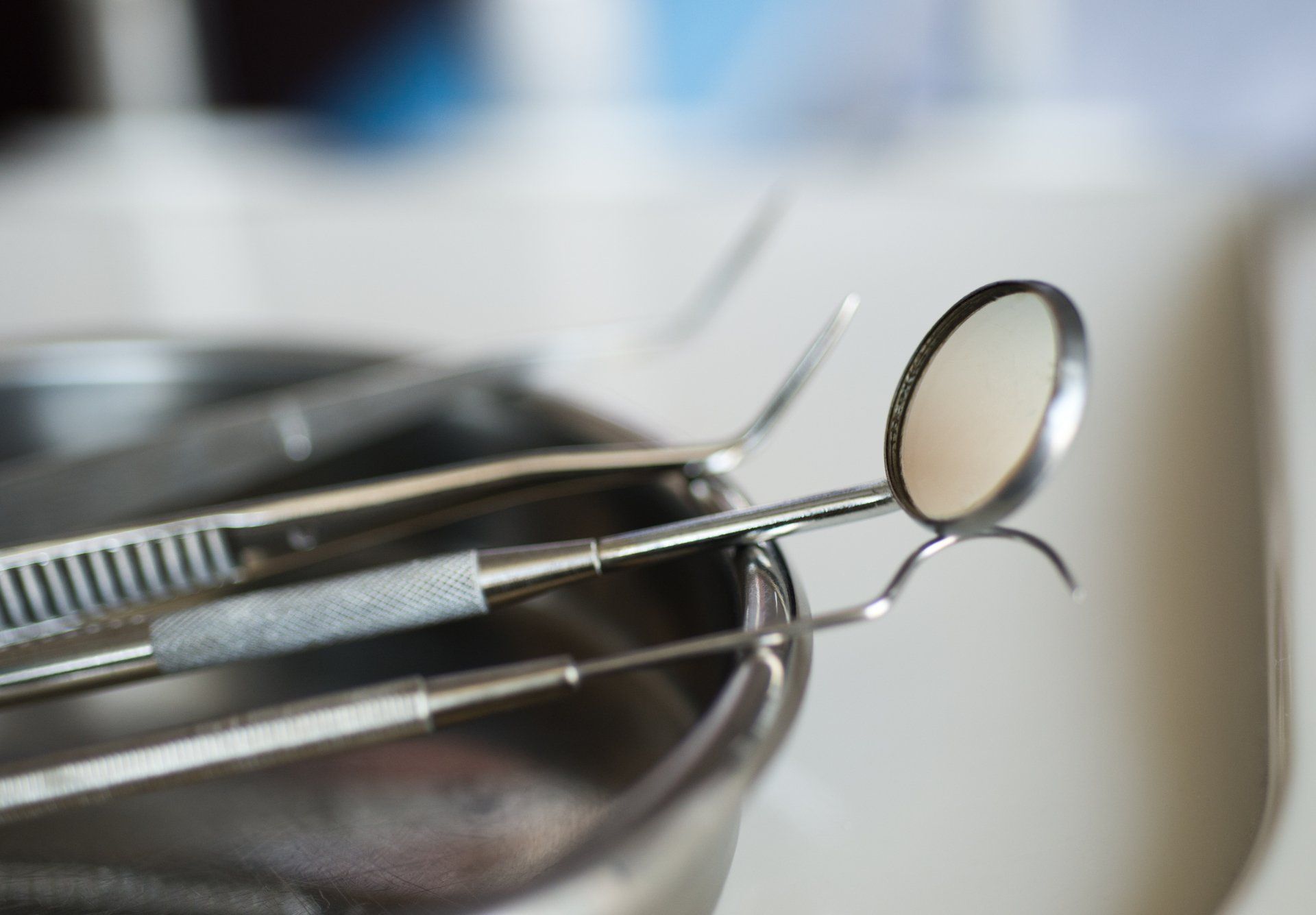 A dental mirror is sitting on top of a tray of dental instruments.