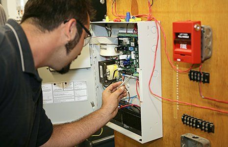 Worker Repairing Fire Alarm — Great Bend, KS — Pryor Automatic Fire Sprinkler Worker Repairing Fire Alarm — Great Bend, KS — Pryor Automatic Fire Sprinkler
