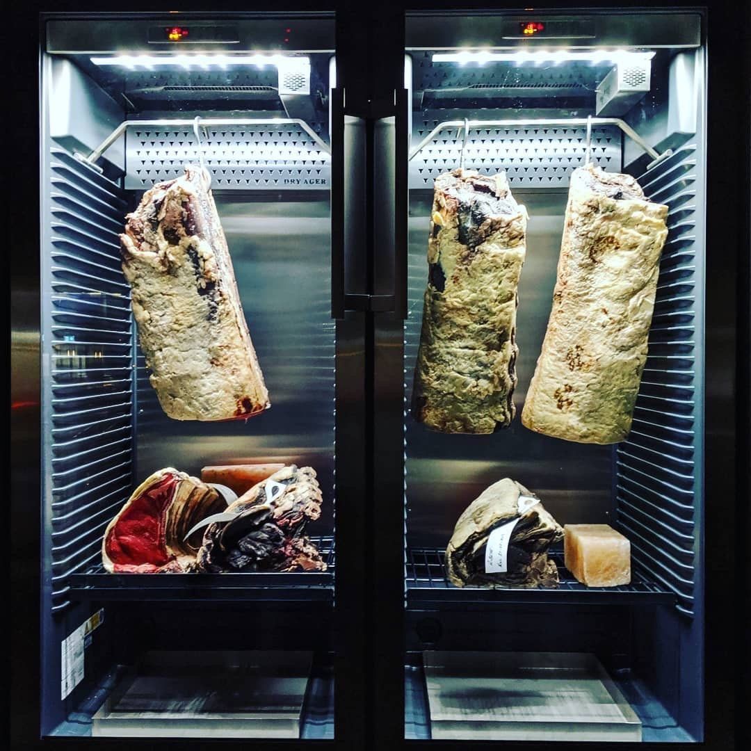 Two glass refrigerators with hanging cured meat 