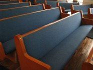 Rows of blue cushioned church pews with wooden frames.