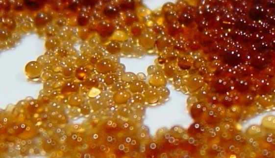 A close up of a pile of brown beads on a white surface.