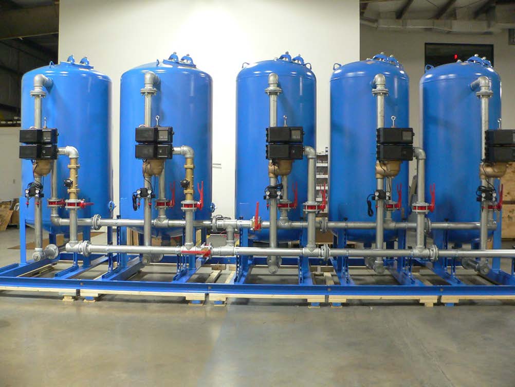 A row of blue tanks are lined up in a warehouse