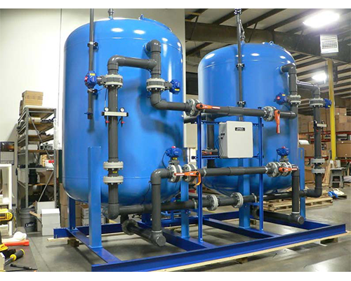 Two blue tanks with pipes attached to them in a warehouse