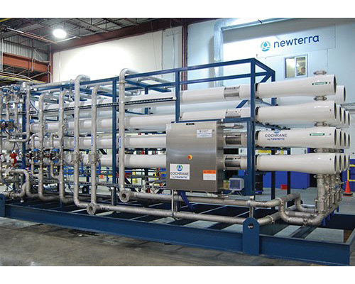 A row of white pipes are lined up in a warehouse.