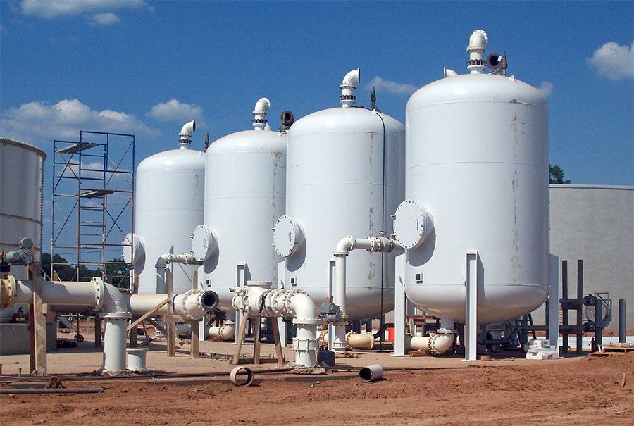 A row of white tanks are lined up in a field