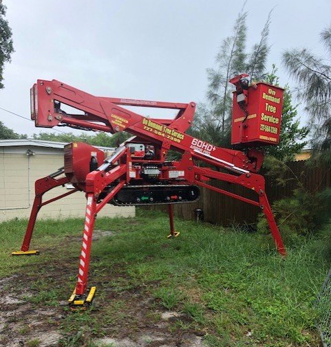 Red spider lift on tracks, extended, in a yard; for tree service.