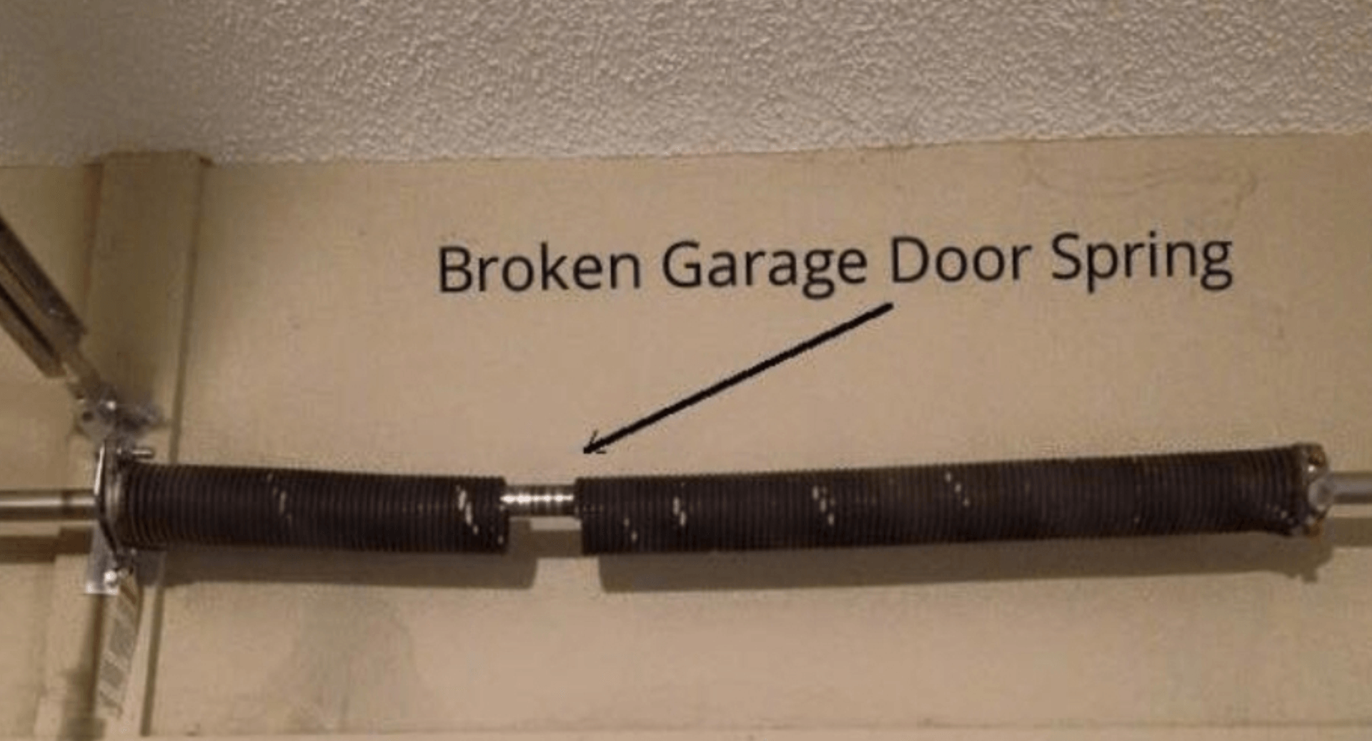 A broken garage door spring  is hanging on a wall.