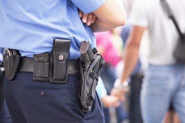 A police man wearing uniform and a gun in his waist band