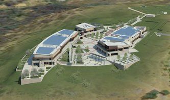 Aerial view of a modern complex with solar panels, a central courtyard, and surrounding green hills.