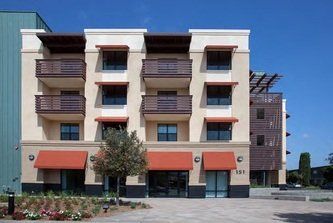 Multi-story building with tan exterior, balconies, and awnings.