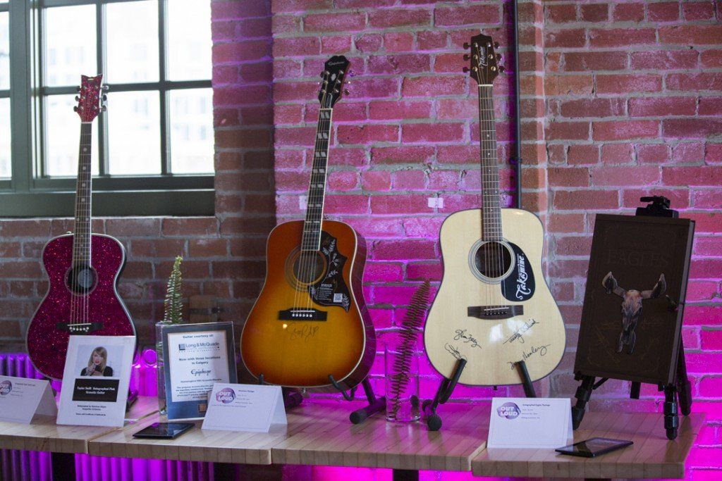 Three guitars are sitting on a table in front of a brick wall.