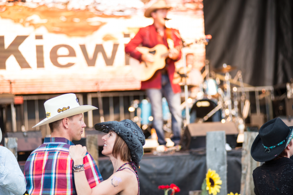 A man is playing a guitar on stage while a woman is dancing in front of him.
