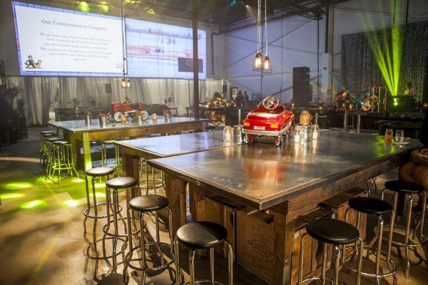 A large room with tables and stools and a red car on the table.
