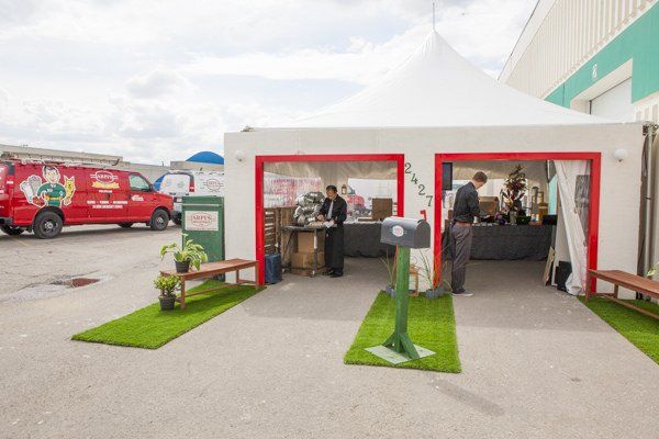A red van is parked in front of a white tent.
