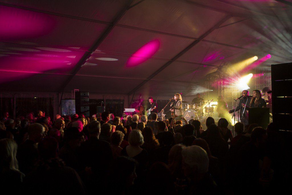 A crowd of people are watching a band on stage at a concert.