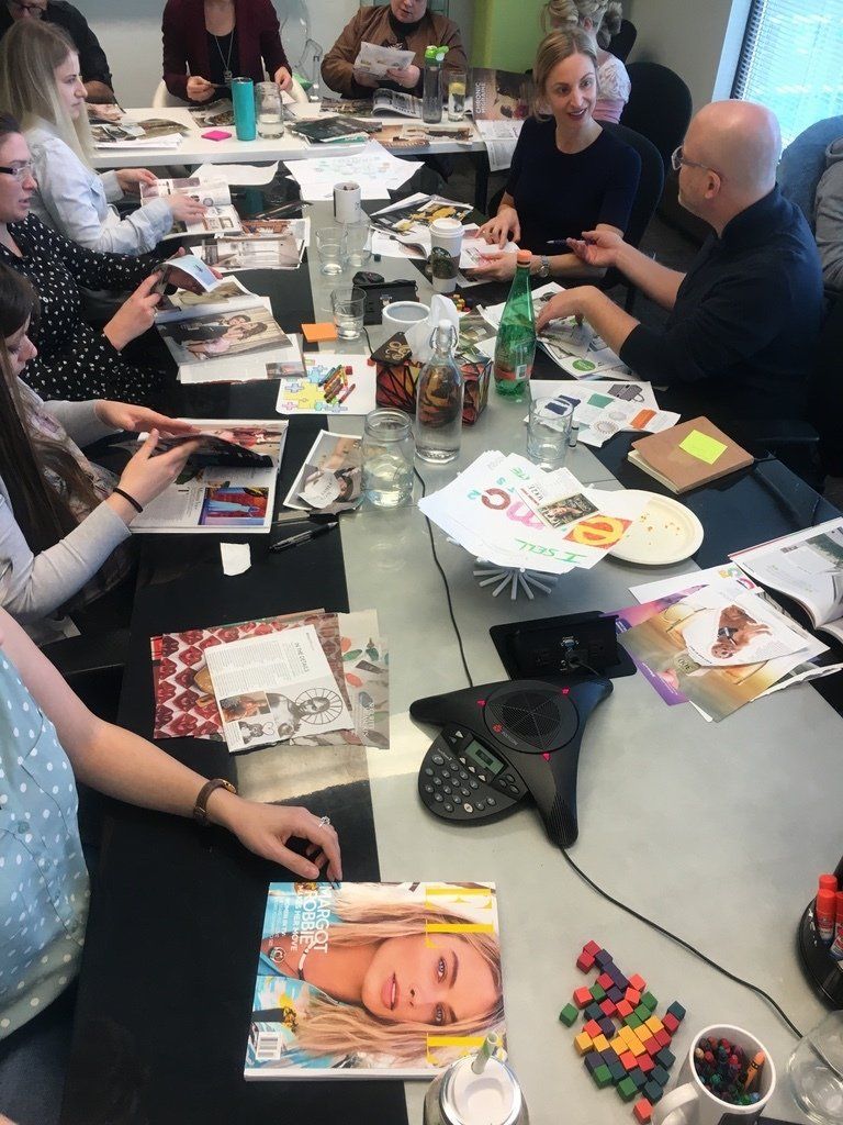 A group of people are sitting around a table with magazines on it.