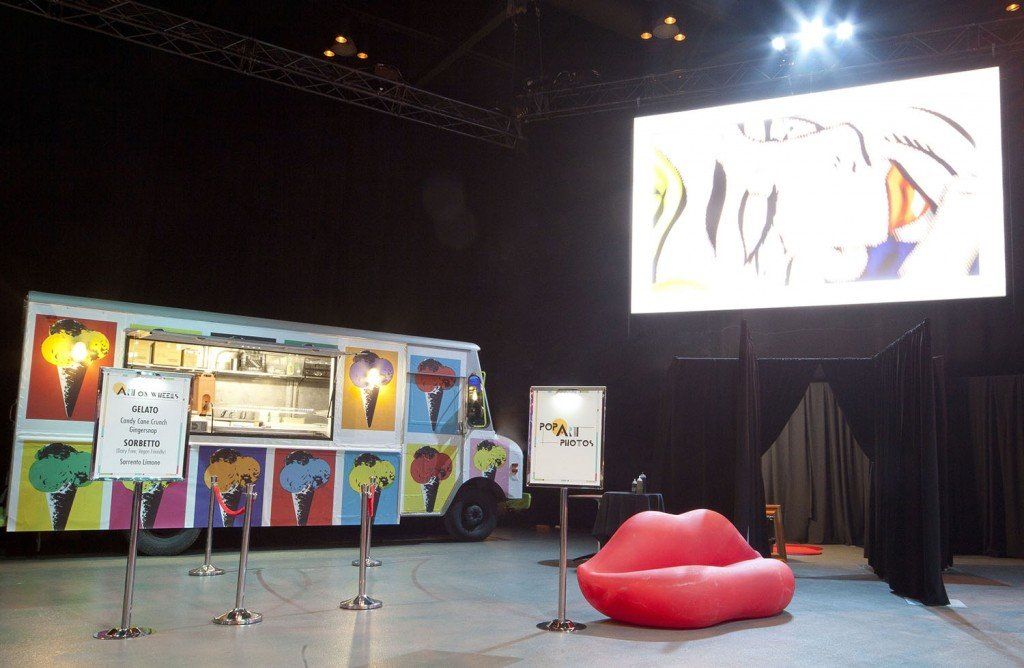 A food truck is parked in front of a large screen