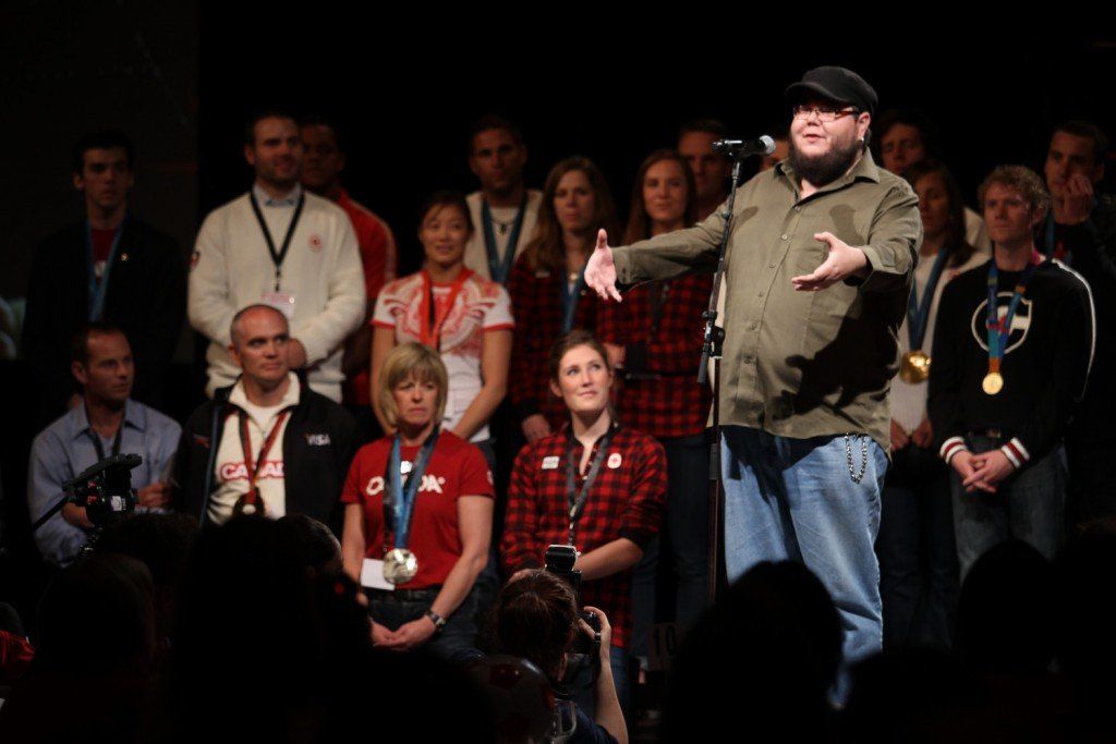 A man is standing in front of a microphone in front of a crowd.