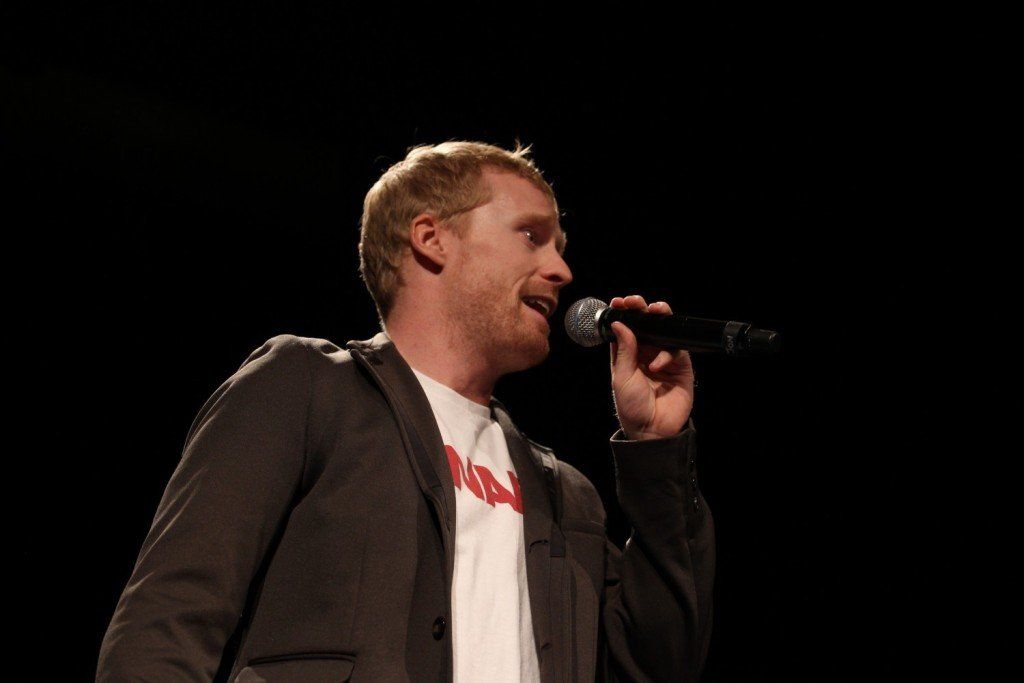 A man is singing into a microphone in a dark room.