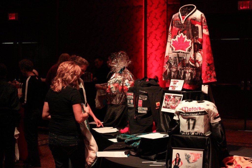 A group of people are standing around a table with a hockey jersey on it.