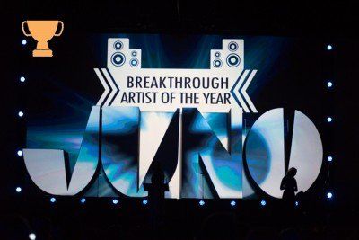 A man is standing in front of a stage that says breakthrough artist of the year