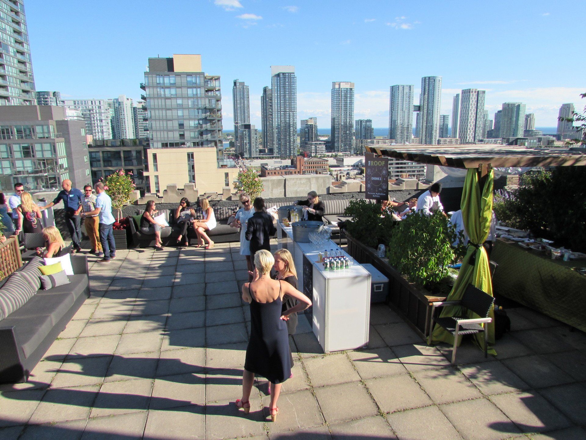 A group of people are gathered on a rooftop with a city skyline in the background