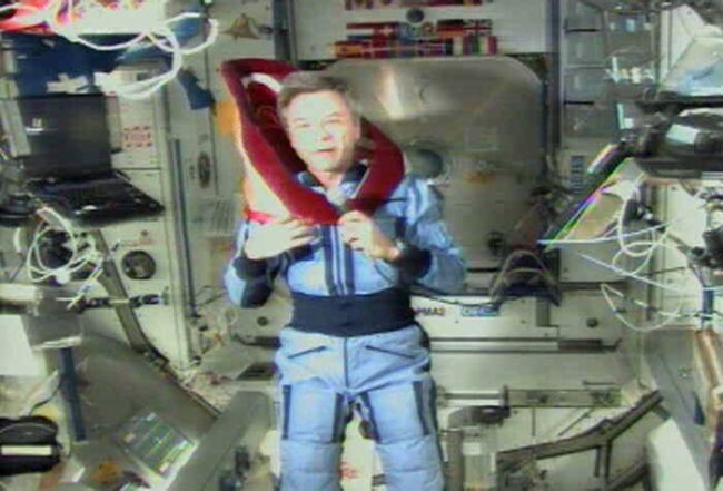 A man in a space suit is holding a red object