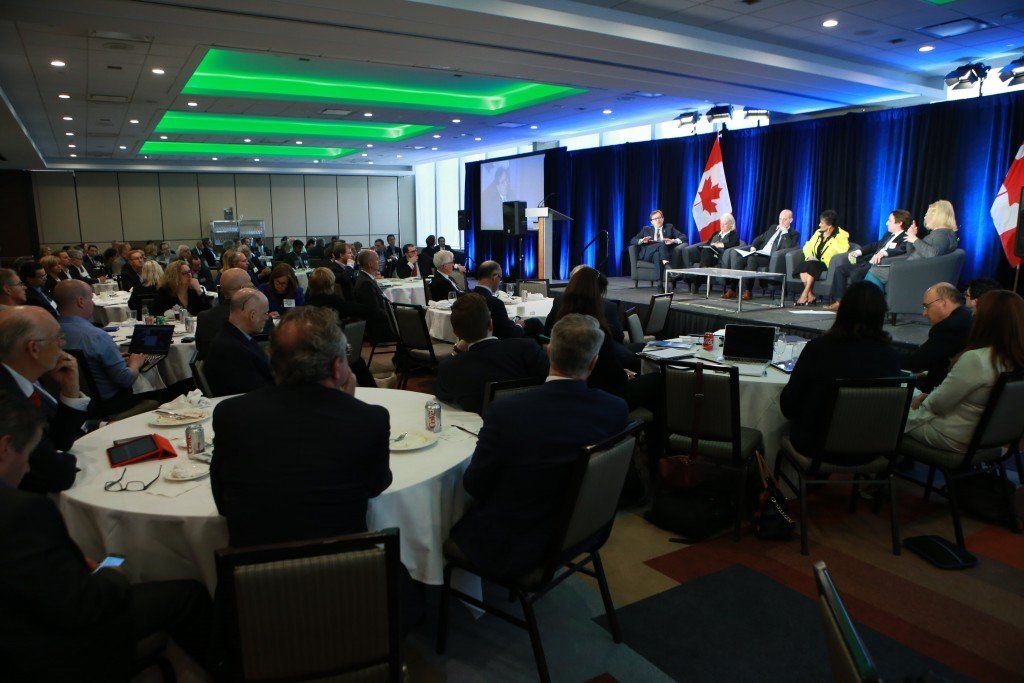 A large group of people are sitting at tables in a conference room.