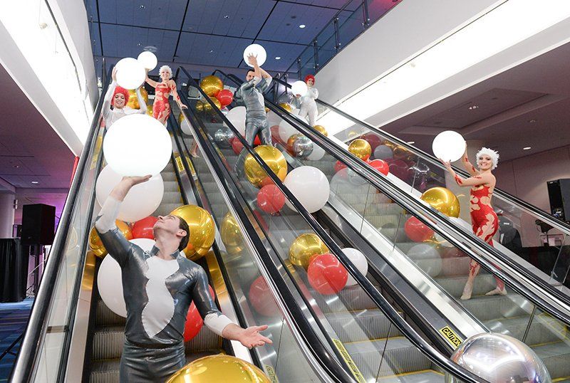 A group of people are standing on an escalator holding balloons.