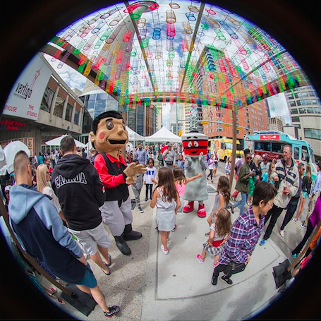 A fisheye view of a crowd of people standing around a mascot