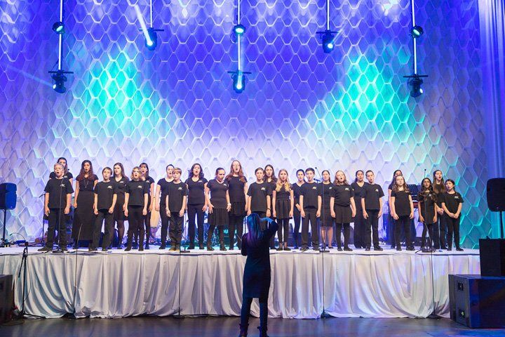 A large group of children are singing on a stage.