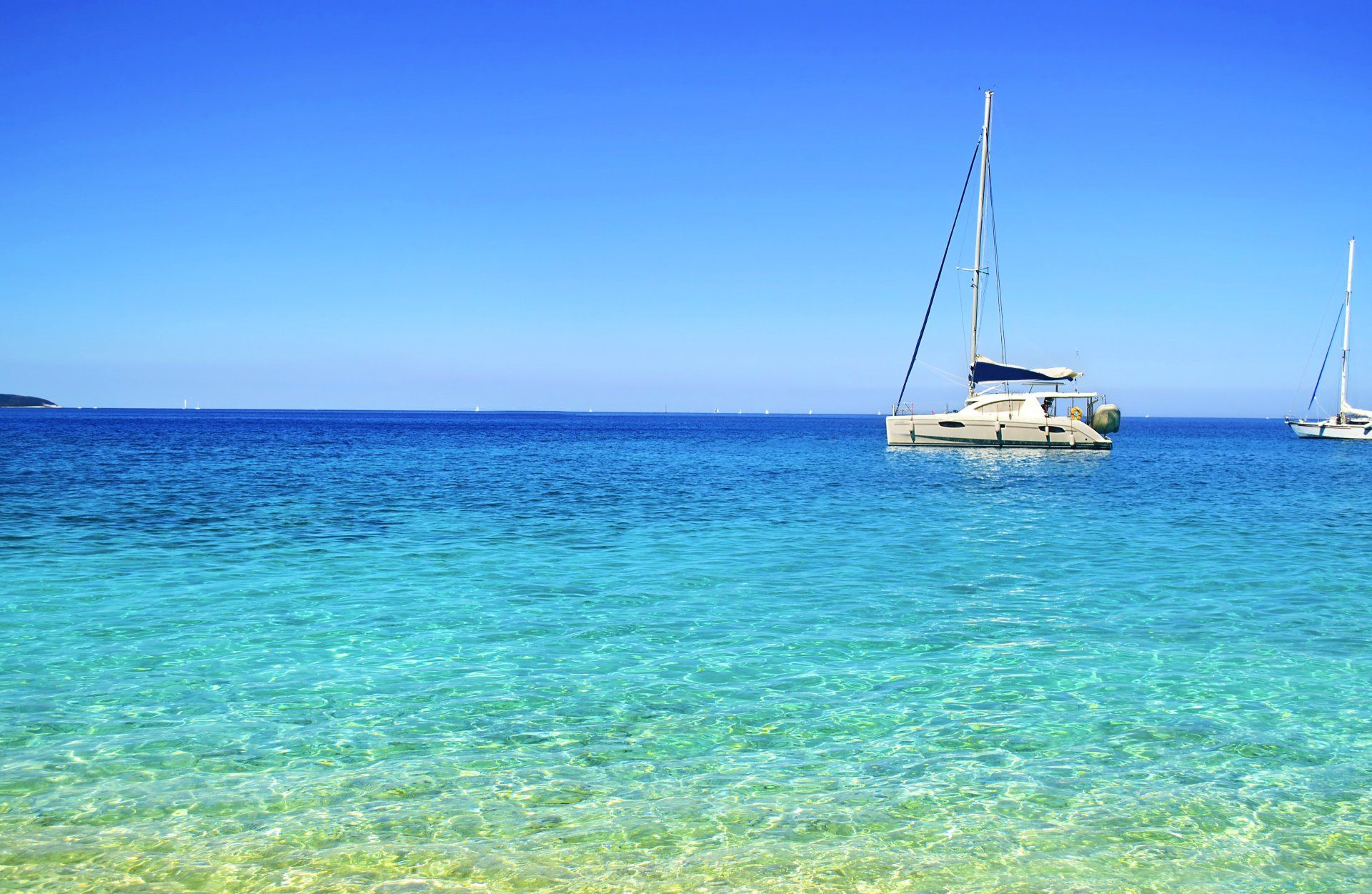 A sailboat is floating on top of a turquoise ocean.