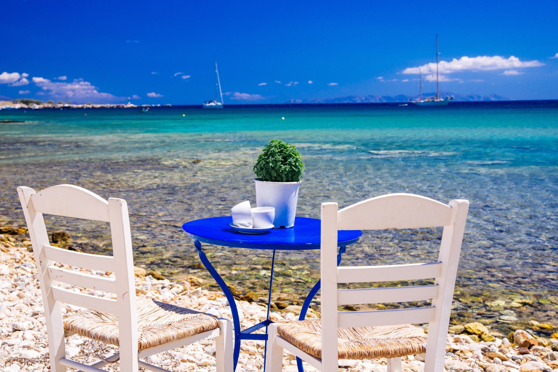 Two chairs and a table on the beach near the ocean.