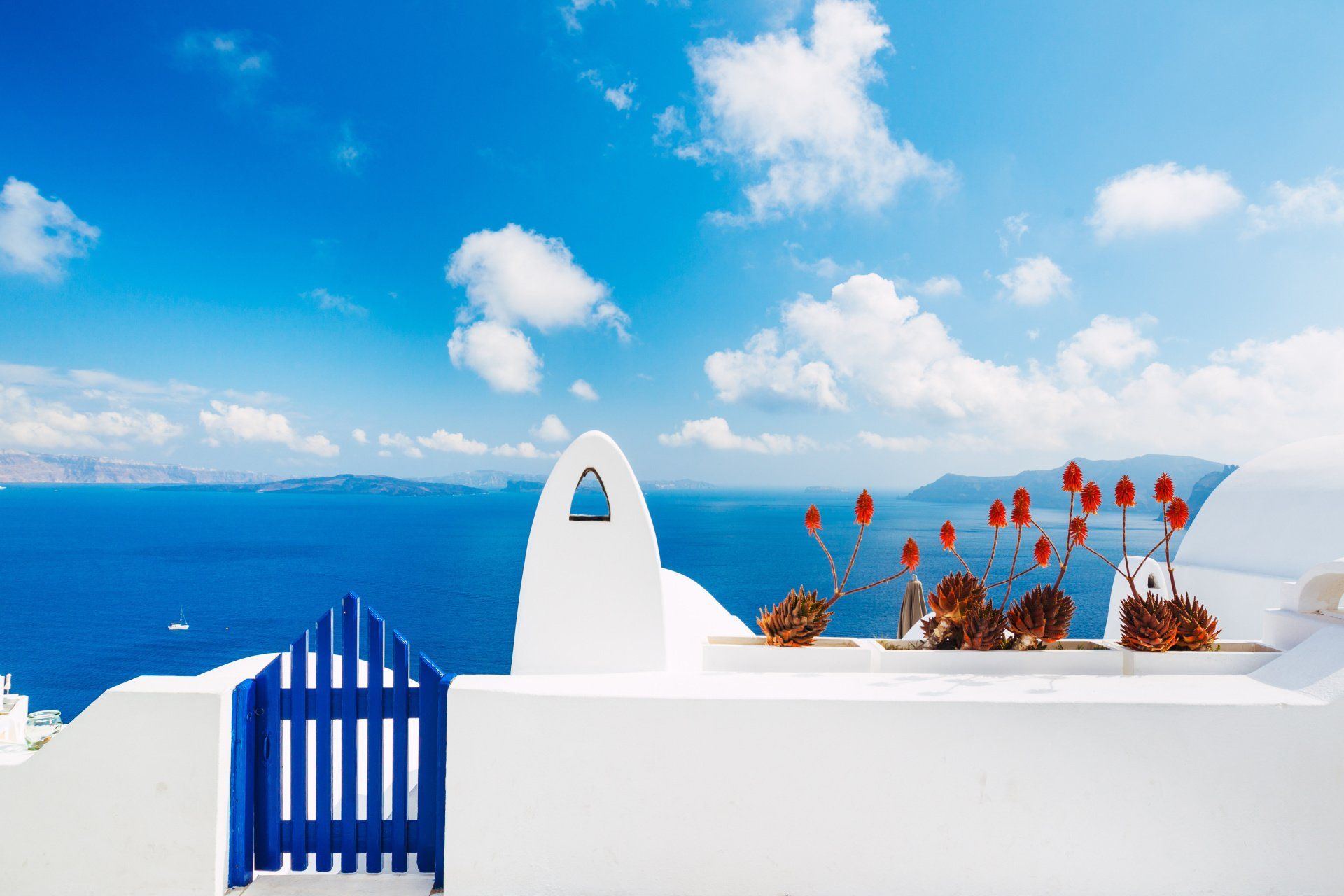 A white building with a blue gate overlooking the ocean.